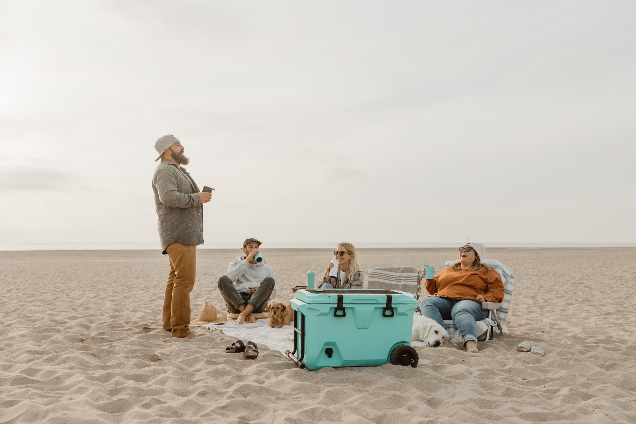 group of people sitting on the beach at sunset.